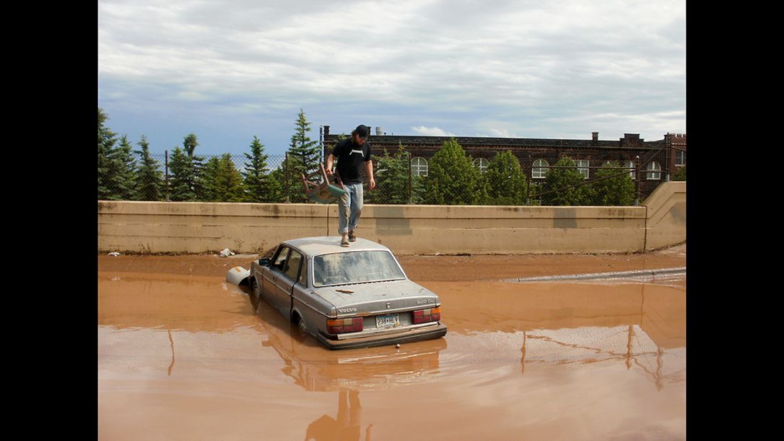 Ian Koivisto drove his car into this flooded area of Dultuh, Minnesota, early Thursday and then had to swim to safety. Richard Thomas, a CNN iReporter, took this photo of Koivisto atop his car.