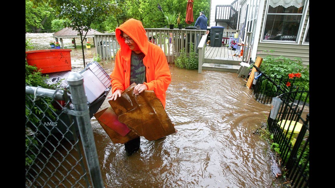 Connie Strong clears debris from her neighbor's yard in Duluth's Lincoln Park neighborhood Wednesday, June 20, after record rainfall. Flood warnings remain in effect for parts of six counties around Duluth.