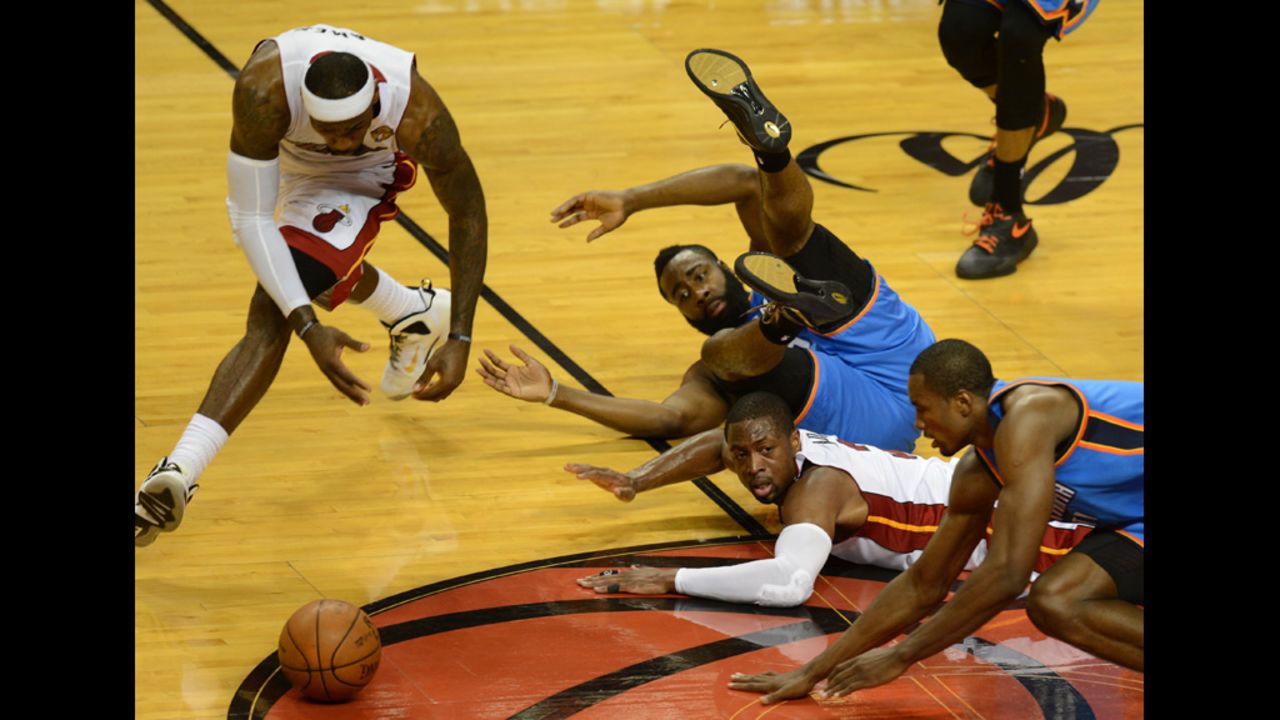 LeBron James, left, and the fallen Dwyane Wade, center, of the Heat go for the ball before the tumbled James Harden, center top, and Serge Ibaka, right, of the Thunder.