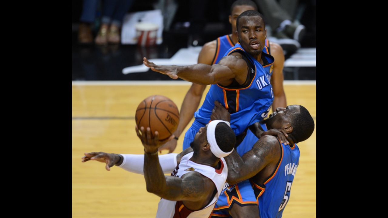 LeBron James, left, of the Heat goes to the basket against Serge Ibaka, center, and Kendrick Perkins, right, of the Thunder.