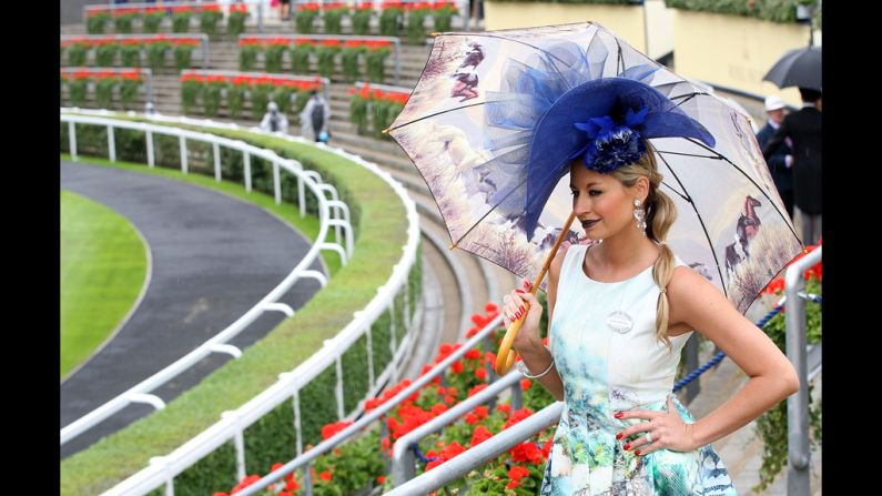 A woman poses with a striking hat and equine-themed umbrella.