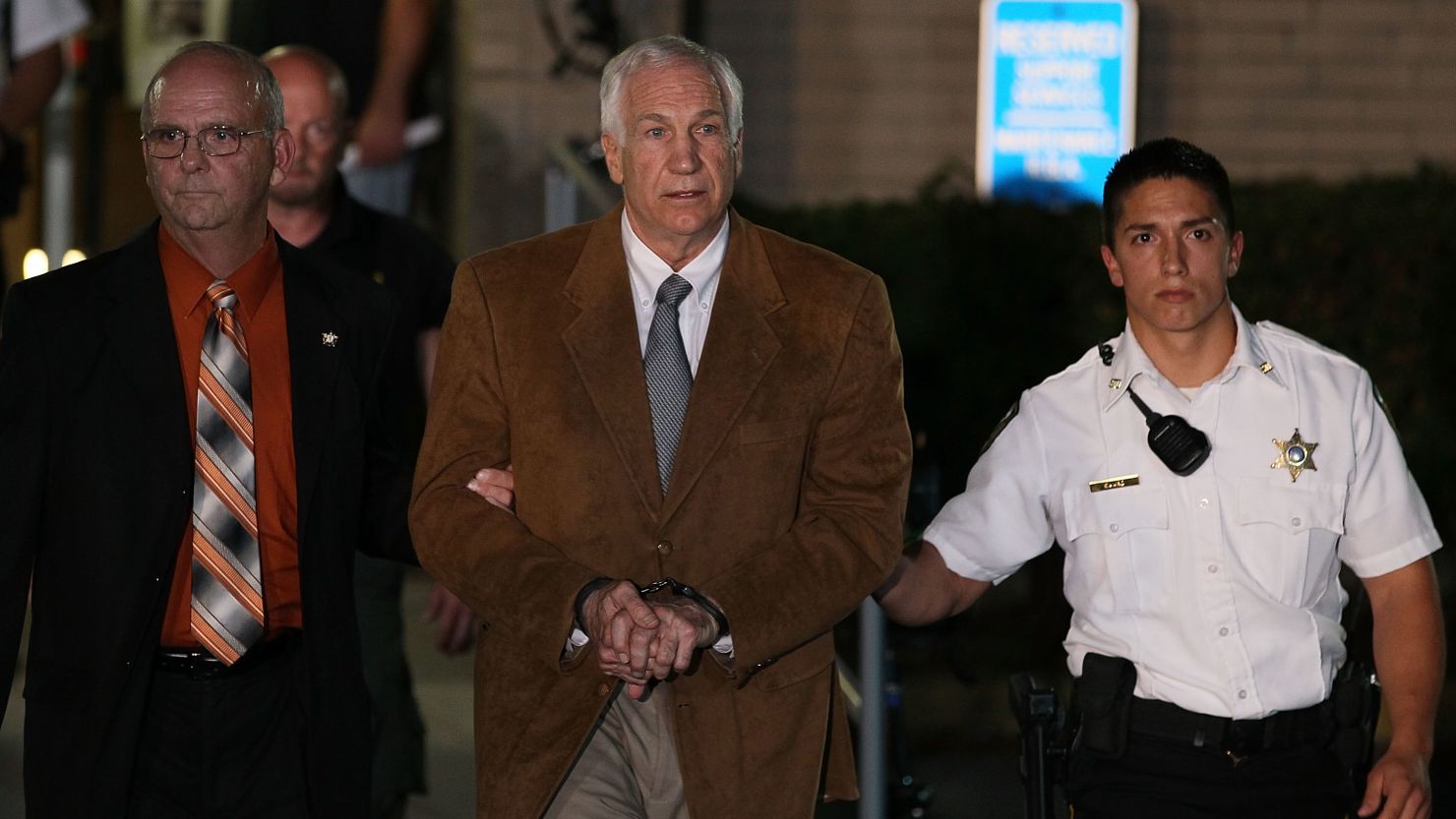 Jerry Sandusky leaves court in handcuffs after being convicted in his child sex abuse trial in Bellefonte, Pennsylvania. 