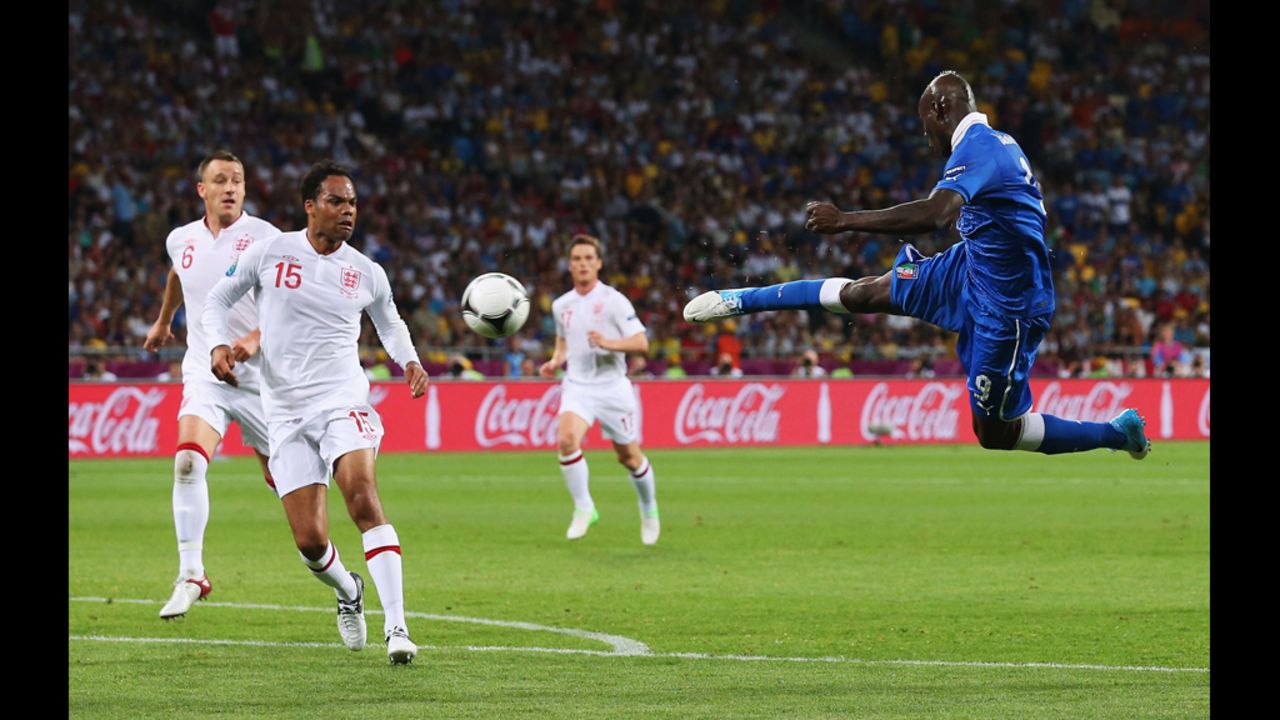 Mario Balotelli of Italy strikes the ball as Joleon Lescott of England looks on.