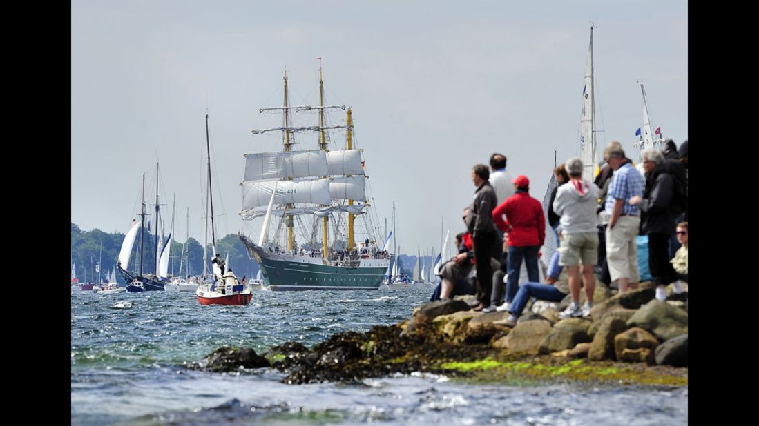 Visitors stand on the rocky shore, watching the Alexander von Humboldt II pass by.