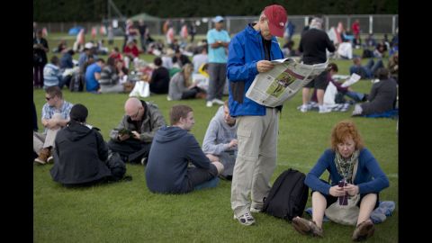Tennis fans pass the time as they wait in line for tickets outside the stadium June 26.