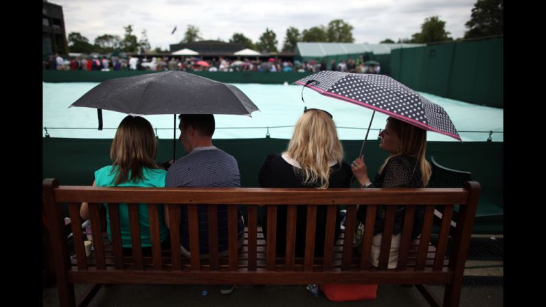 Spectators wait for play to resume after Tuesday's matches were halted due to rain June 26.