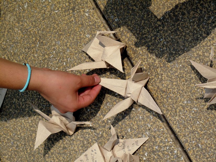 An activist in Mexico City places an origami bird on a sidewalk as part of an art project to promote peace.