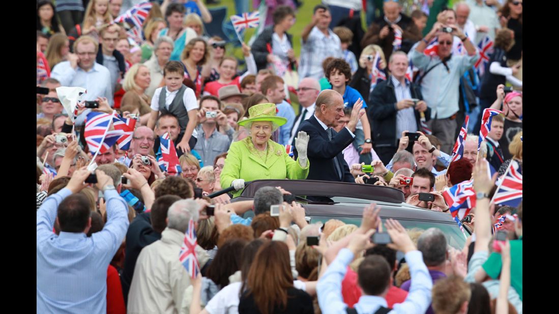 Queen Elizabeth II and Prince Phillip ride through the streets of Belfast, Northern Ireland, on Wednesday, June 27, surrounded by supporters.