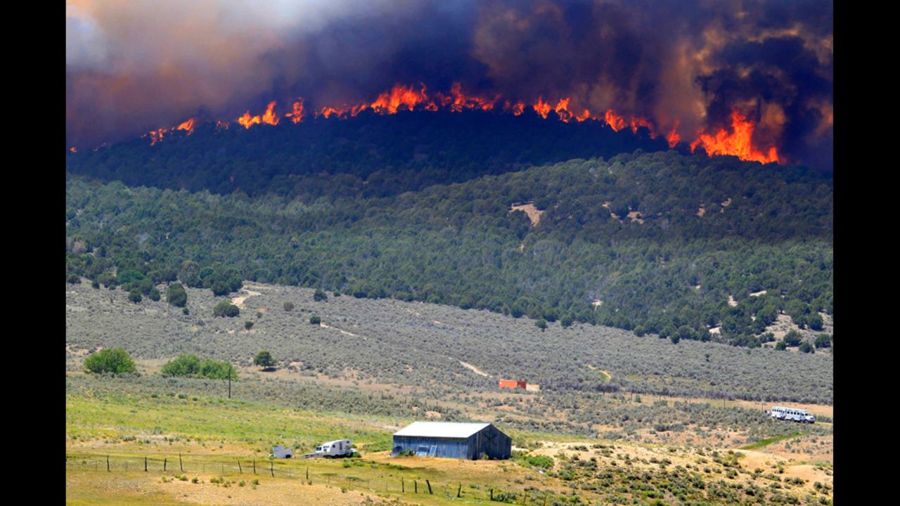 A wall of fire makes its way down a hillside toward a farm north of Fairview, Utah, on Tuesday, June 26. The Wood Hollow Fire, one of at least three wildfires burning in Utah, has grown to nearly 39,000 acres.
