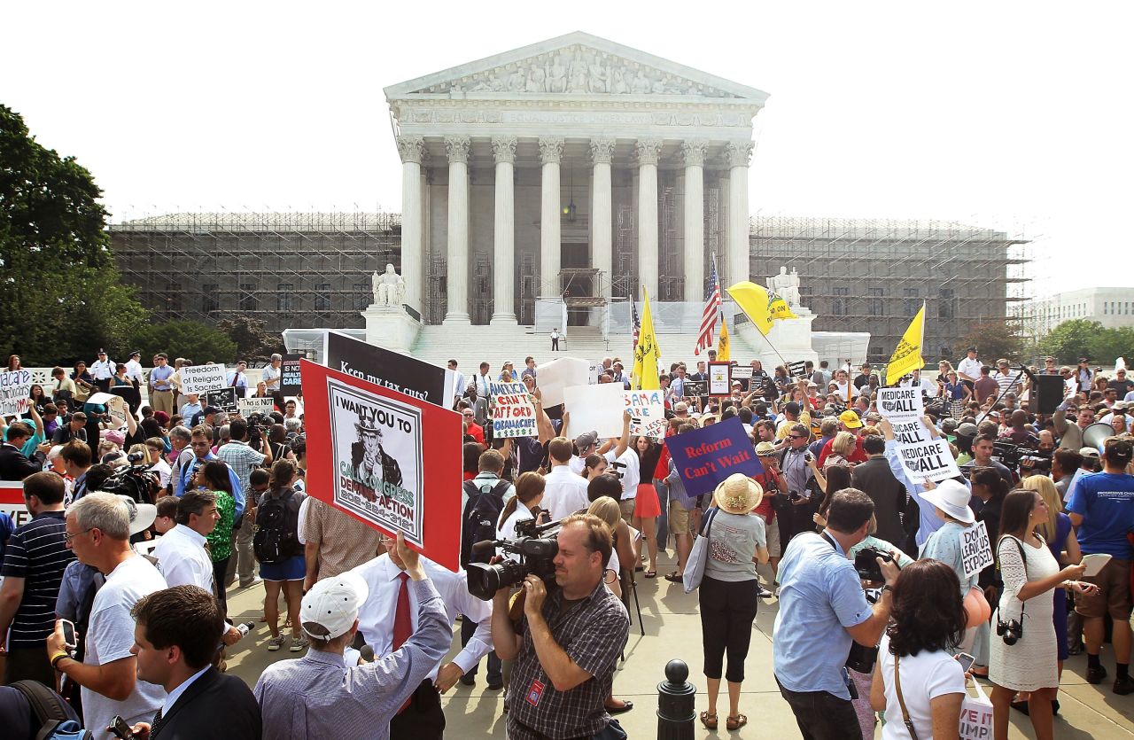 Journalists and supporters and protesters of the health care law gather outside the Supreme Court after the justices ruled in favor of its constitutionality in a narrow decision.