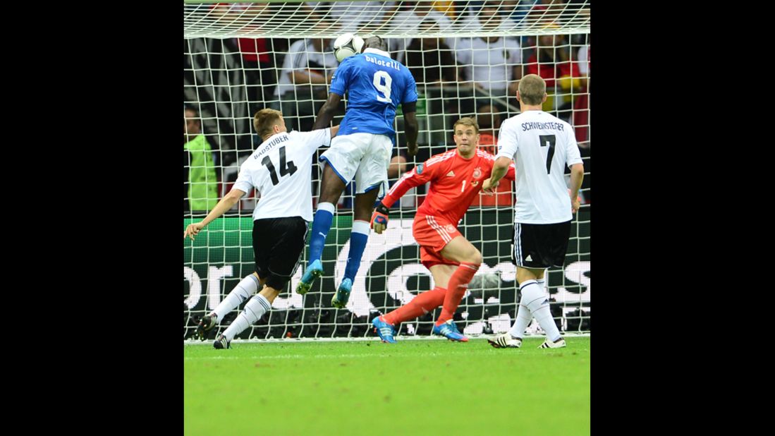 Italian forward Mario Balotelli, in blue, heads the ball into the goal, scoring the first goal in the match.