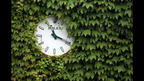 A Wimbledon tournament clock is visible through leaves Friday at the All England Lawn Tennis and Croquet Club in London.