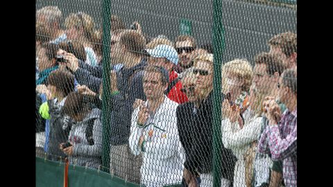 The crowd gathers and watches from behind a fence Friday. 