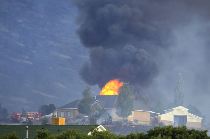 A house is engulfed in flames as fire crews fight to contain it at the Rose Crest fire in Herriman, Utah, on Friday, June 29. Crews are fighting to contain six separate blazes in the state.