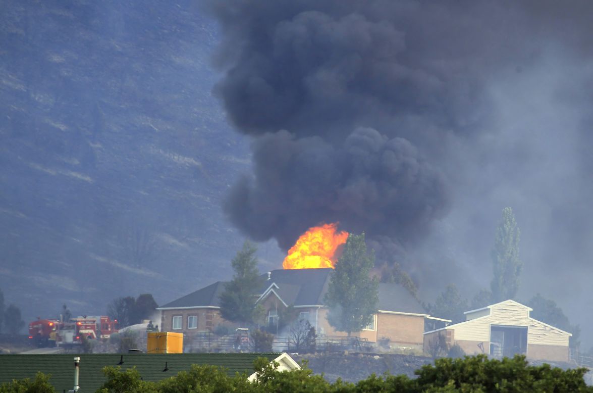 A house is engulfed in flames as fire crews fight to contain it at the Rose Crest fire in Herriman, Utah, on Friday, June 29. Crews are fighting to contain six separate blazes in the state.