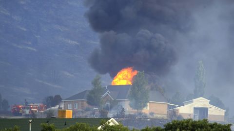 A house is engulfed in flames as fire crews fight to contain it at the Rose Crest fire in Herriman, Utah, on Friday, June 29. Crews are fighting to contain six separate blazes in the state.