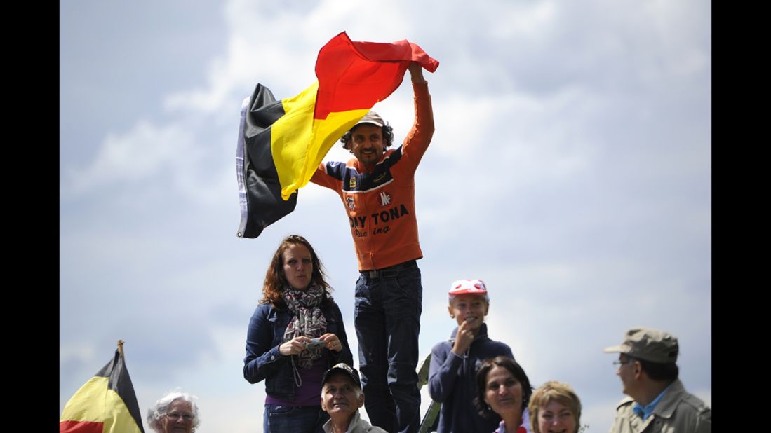 A spectator waves the Belgian flag as fans wait for riders to pass along the Stage 1 route on Sunday.
