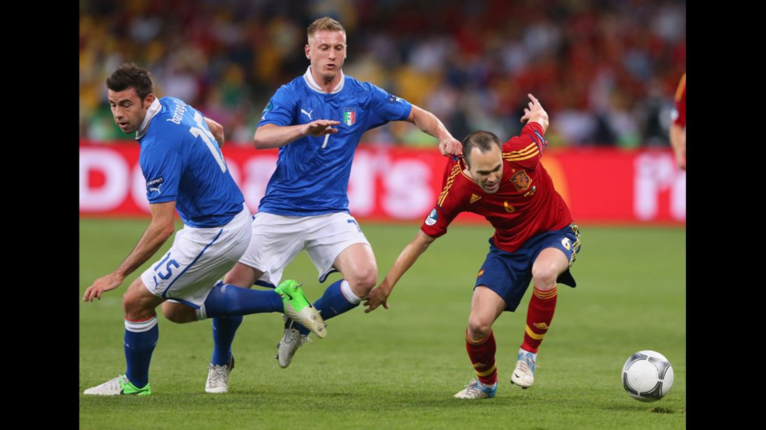 Ignazio Abate of Italy, center, grabs the shirt of Spain's Andres Iniesta.
