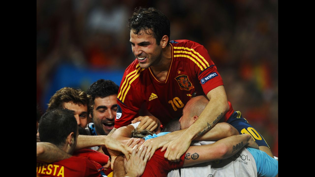 Cesc Fabregas of Spain jumps on his teammates as they celebrate after Fernando Torres scored his team's third goal against Italy.
