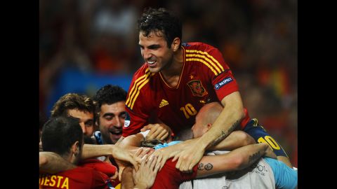 Cesc Fabregas of Spain jumps on his teammates as they celebrate after Fernando Torres scored his team's third goal against Italy.