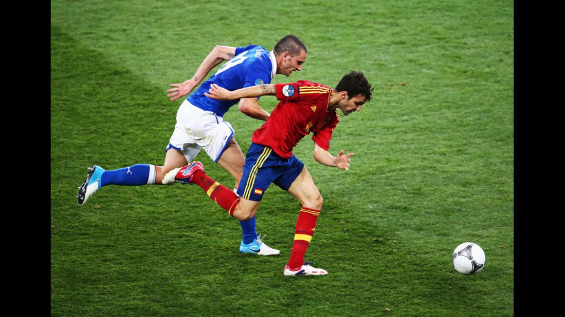 Cesc Fabregas of Spain runs with the ball past Leonardo Bonucci of Italy.