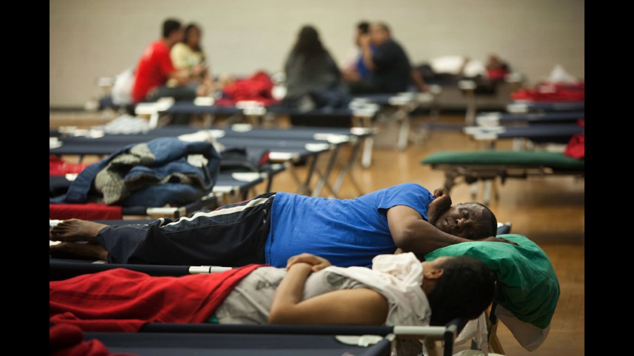 Tek Measho, center, and others rest on cots in a Red Cross shelter set up at Northwestern High School in Hyattsville, Maryland, after the heavy storms knocked out power to their apartment building.