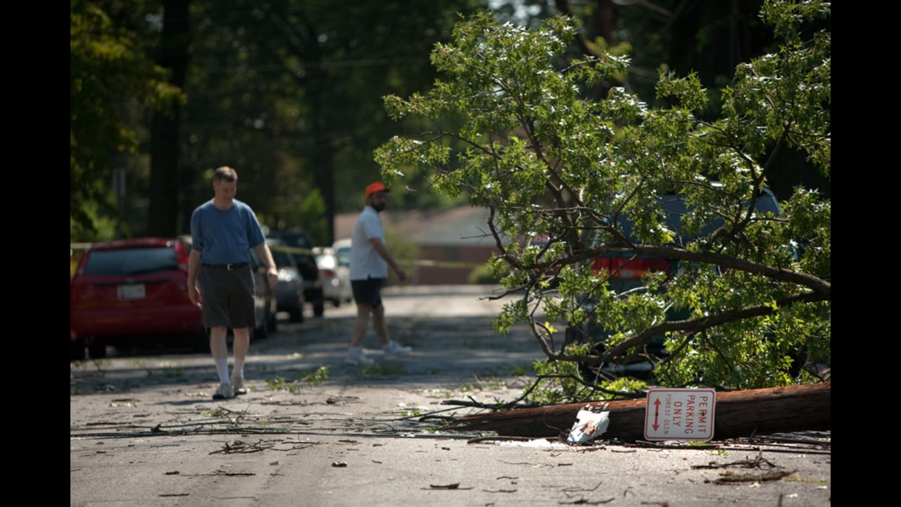 Neighbors inspect a downed tree on a heavily damaged block in Forest Glen, Maryland.