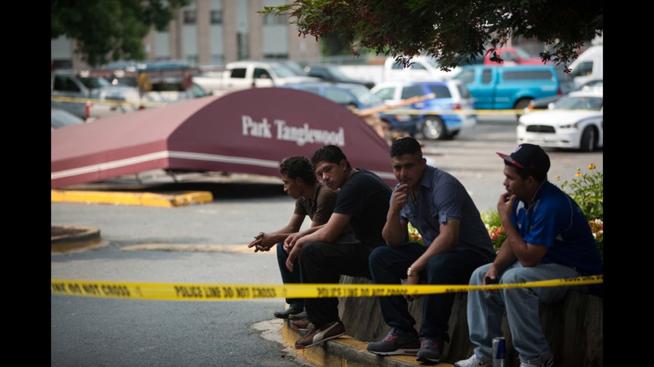 Residents sit in the parking lot of  the seven-story Park Tanglewood Apartments in Riverdale, Maryland, after heavy winds tore off much of the building's roof, forcing all of the residents to be evacuated from the building.