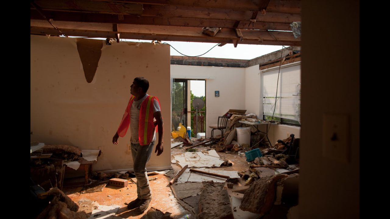 Annery Santos, an employee of CRS Roofing, walks through a damaged apartment in the Park Tanglewood Apartments in Riverdale.