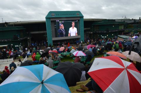 Spectators take shelter under umbrellas on "Murray Mount" for the match between Britain's Andy Murray and Croatia's Marin Cilic.