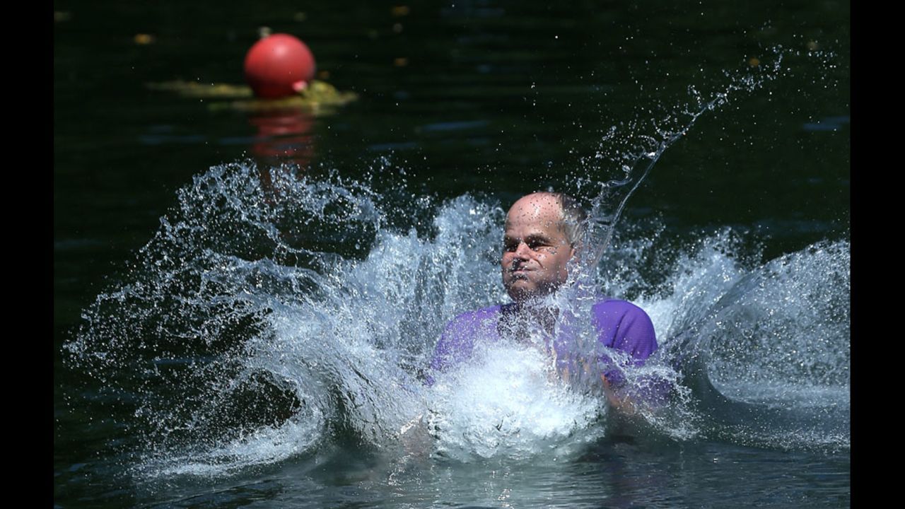 Gene Holmes splashes into a quarry lake after jumping from a rope swing on Monday, July 2, at the Beaver Dam Swimming Club in Cockeysville, Maryland. 