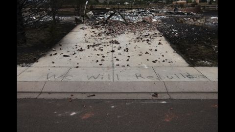 The words "We Will Rebuild" are seen written on the sidewalk in front of a house in Colorado Springs that was destroyed by the fire.