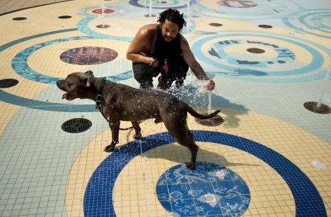 Bryan Moran sprays his dog, Rocky, with water in Washington's Columbia Heights on Sunday. Eastern cities were forecast to approach or break record-high temperatures.