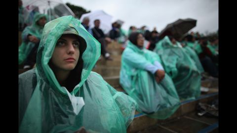 Tennis fans shield themselves from rain at Wimbledon on Monday.