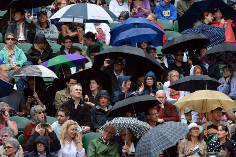 Fans at center court take shelter from the rain under umbrellas during Day Eight of the tournament on Tuesday.