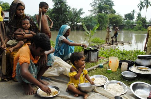 An Indian family eats by a road after their house was washed away by floodwaters at Bulut Village on June 30. The floods have left almost 2 million people homeless.