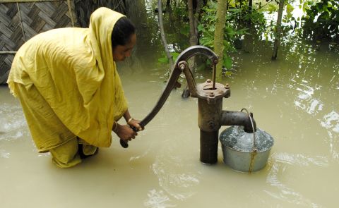 An Indian farmer pumps drinking water from a well in the floodwaters at Bulut Village on June 30. The floods have left at least 95 people dead. 