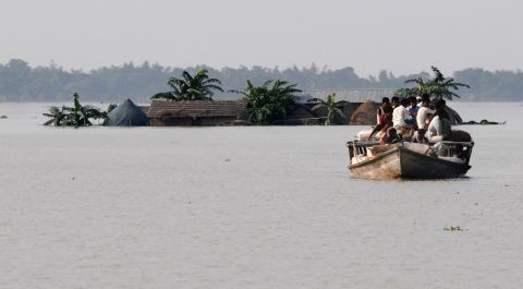 Villagers travel on a boat in the flood affected area of Jhargoan village in Morigoan district on June 29. Almost half a million peolpe are living in relief camps, Prime Minister Manmohan Singh said Monday. 
