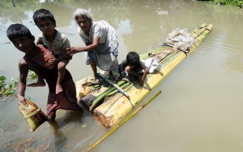 An old lady with her grandchildren climbs off a banana raft in Jhargoan village in Morigoan district on June 29. The flooding has been described as the worst in recent times. 