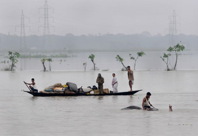 Villagers padddle with their belongings through flood waters in the Pobitora Wildlife Sanctuary, 55 kms from the capital city of the northeastern state of Assam on June 28, 2012. Floodwaters have submerged 90% of the sanctuary. 