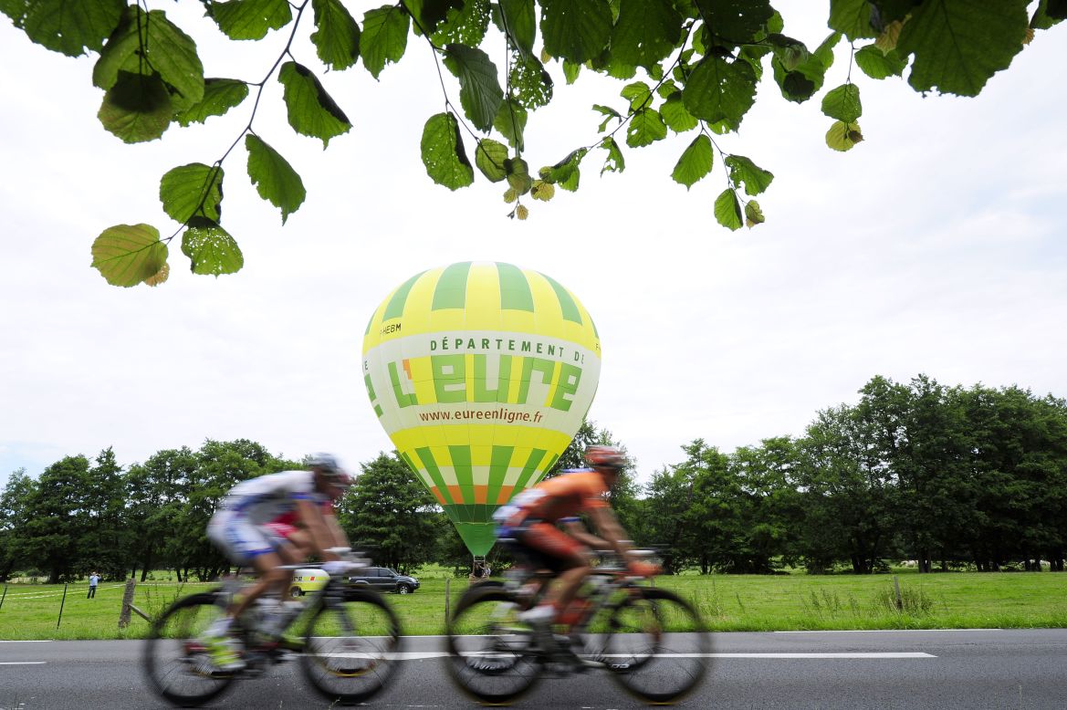 Riders roll past a hot-air balloon sitting in a field along Thursday's course.