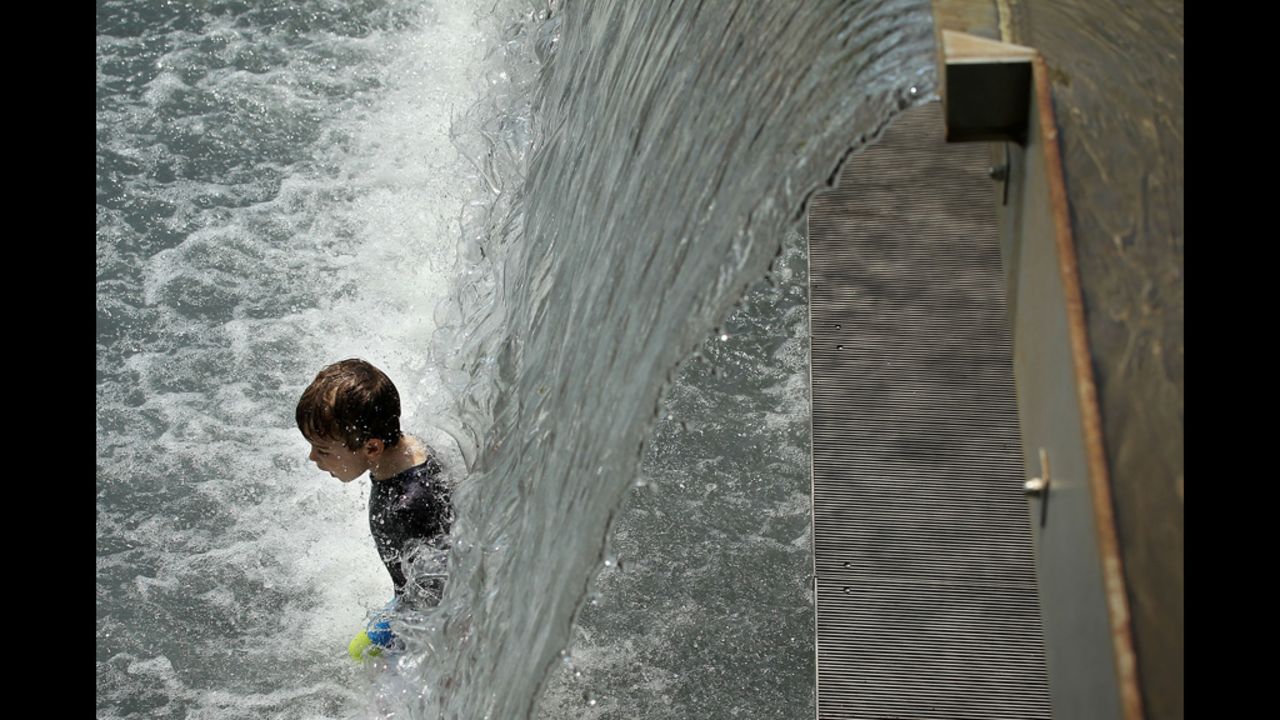 A boy enjoys the waterfall in the Yards Park fountain on Thursday.