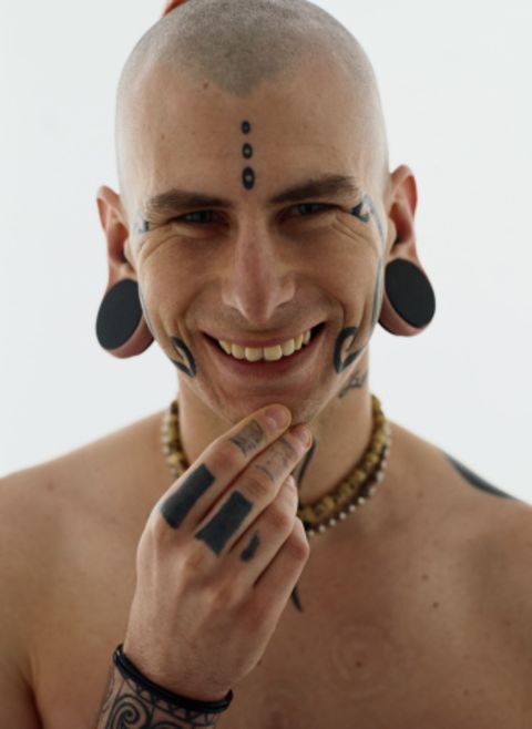 A man displays tattoos, earplugs and a conch piercing.