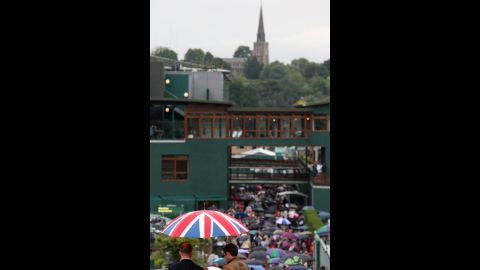 A crowd tries to shelter itself  from the rain Friday on day 11 of the Wimbledon Lawn Tennis Championships.