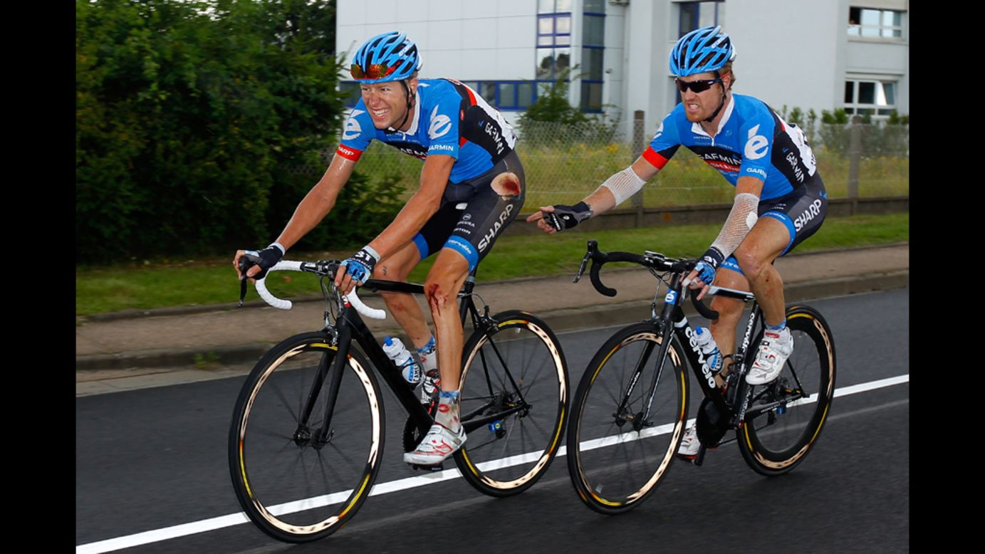 A bloodied Ryder Hesjedal of Canada, riding for Garmin-Sharp, is accompanied by teammate Tyler Farrar of the United States as they ride to the finish of Stage 6 in Metz.  Hesjedal was involved in a crash 25 kilometers from the end of the stage and was separated from the yellow jersey group.