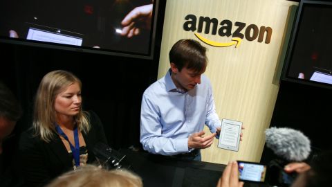 An Amazon employee displays the company's Kindle Touch e-reader last year. Reports say they may be adding a smartphone.
