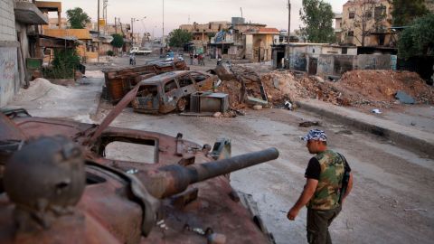 A member of the Free Syria Army walks past a destroyed Syrian forces tank in the town Atareb in northern Aleppo province.