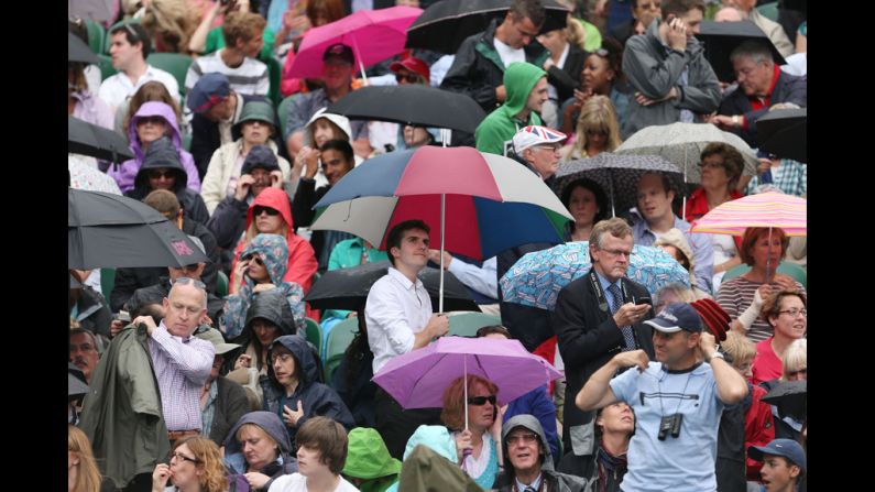 Spectators hide under umbrellas and rain jackets as protection from the rain. <a href="index.php?page=&url=http%3A%2F%2Fwww.cnn.com%2F2012%2F06%2F26%2Ftennis%2Fgallery%2Fwimbledon-best-photos%2Findex.html">See the best WImbledon photos.</a>