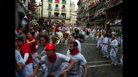 Participants run out of the way of Dolores Aguirre fighting bulls before entering the Estafeta corner.