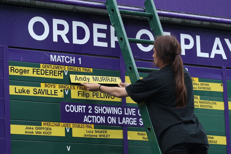 An official changes the order of play board at the All England Lawn Tennis Club ahead of the championship match Sunday.